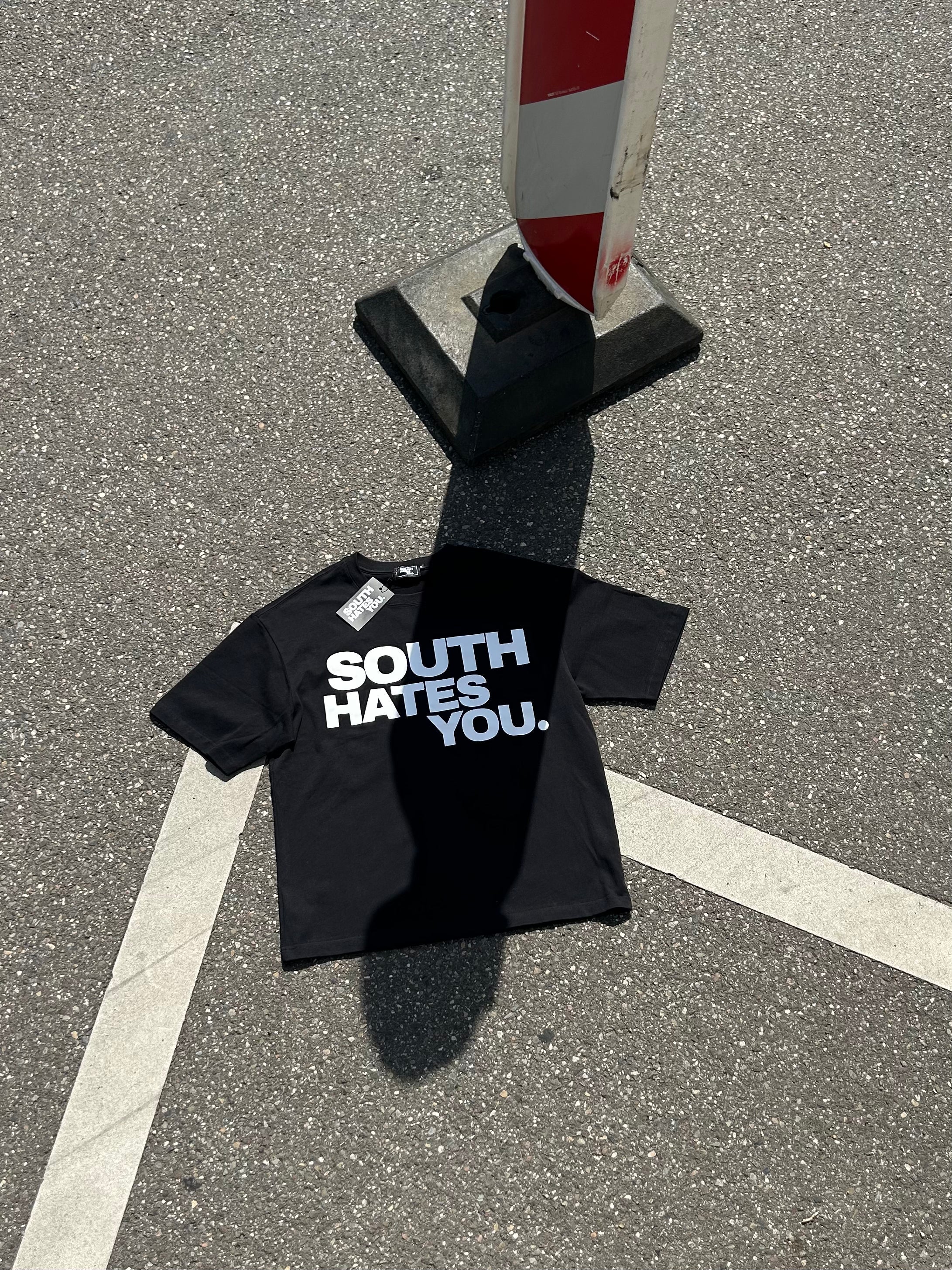 South Hates You. Oversize T-Shirt mit Statement-Print, Streetwear Fotografie auf Asphalt